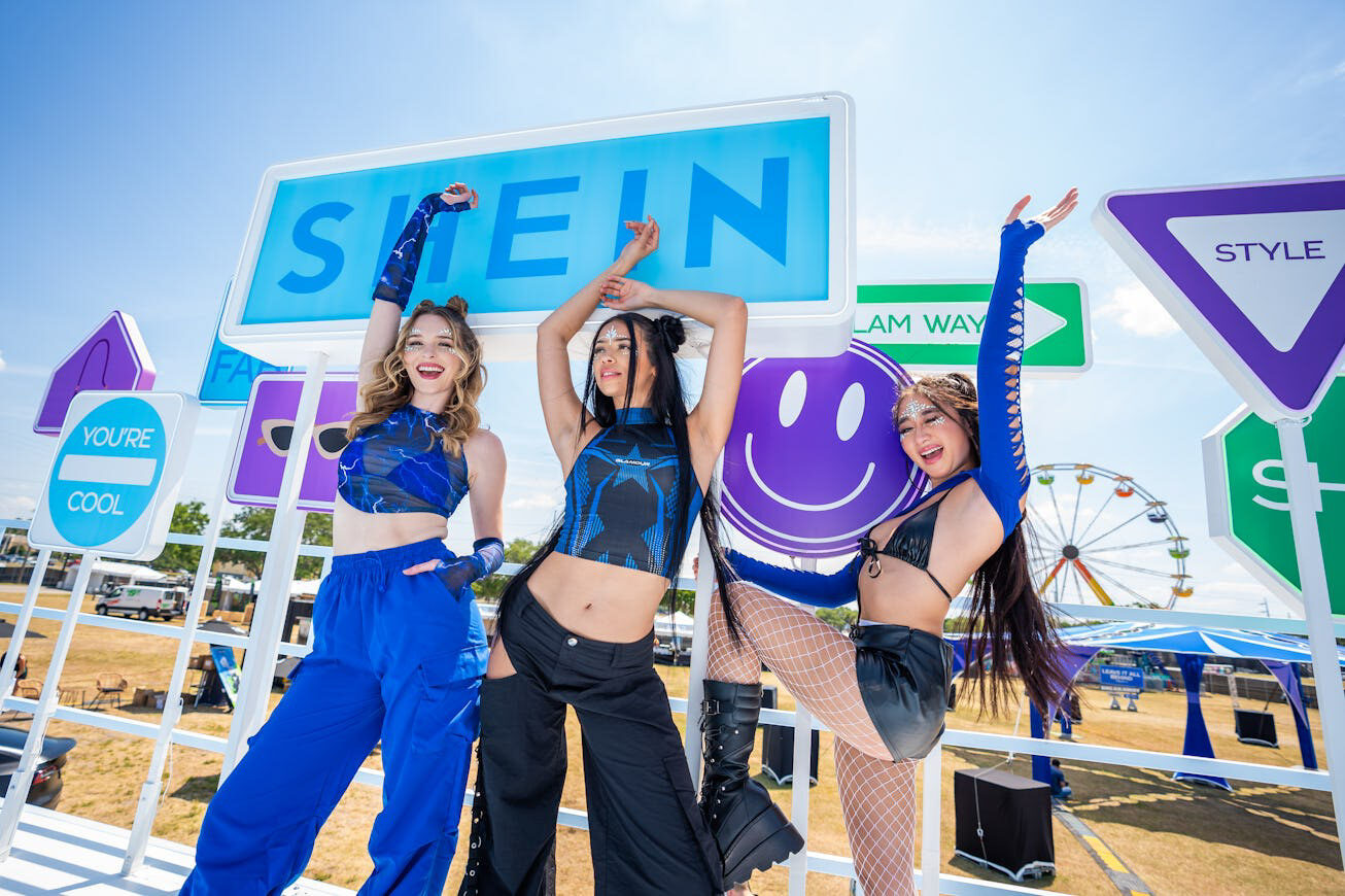 SHEIN performers beneath colorful festival wayfinding signs