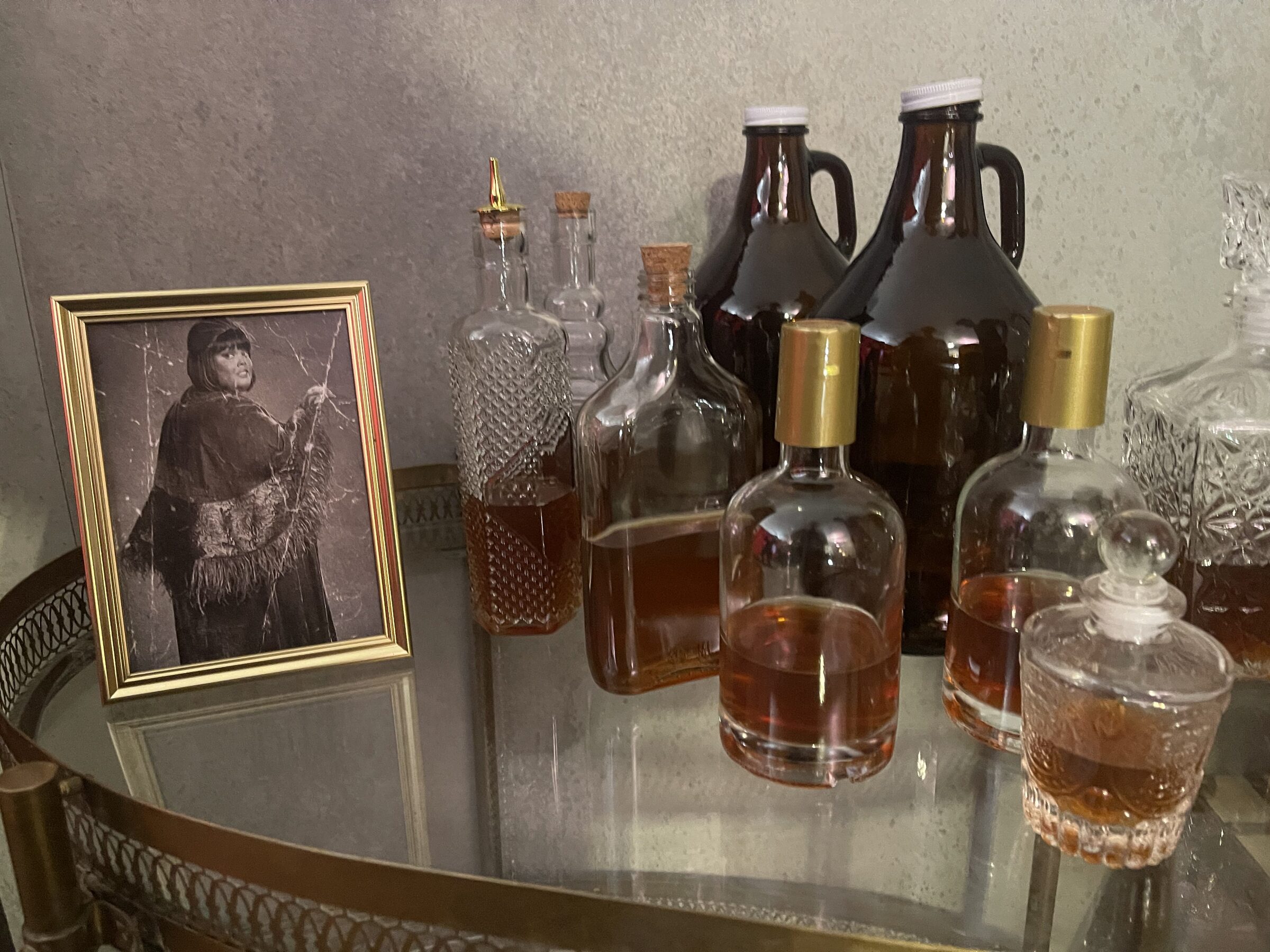 Period bar display with framed Alberta portrait and vintage bottles