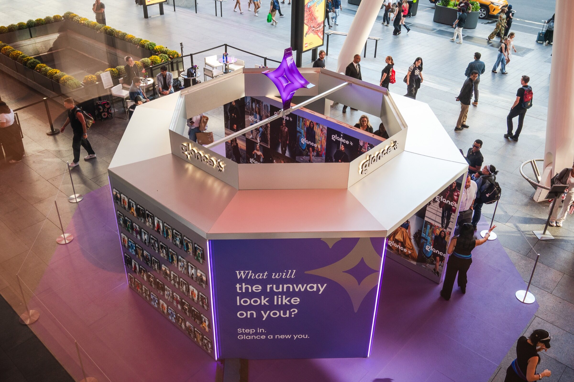 Elevated view of the Glance AI fashion newsstand and guests in Bustle Plaza during New York Fashion Week