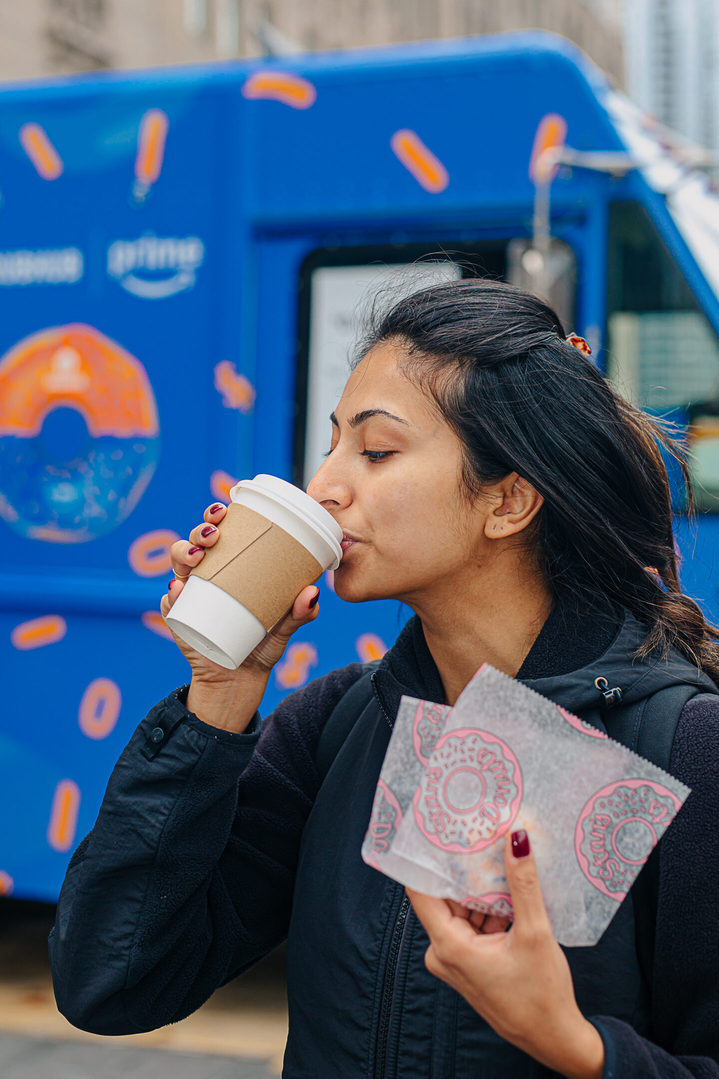 Guest sipping a branded coffee in front of the wrapped truck