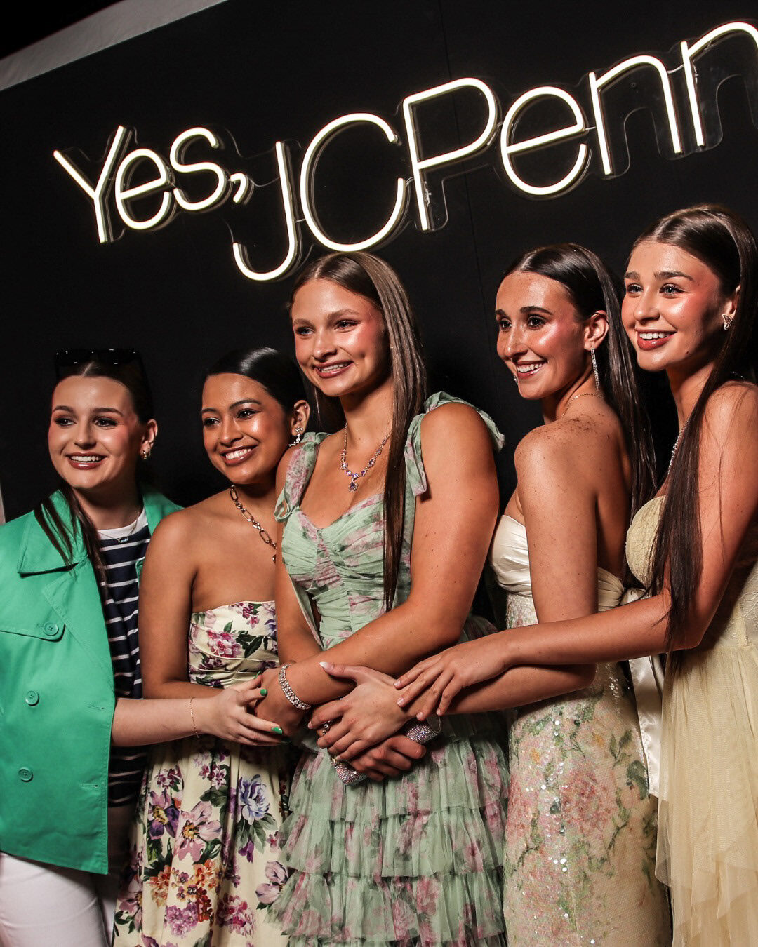 Models gathered beneath illuminated Yes JCPenney signage