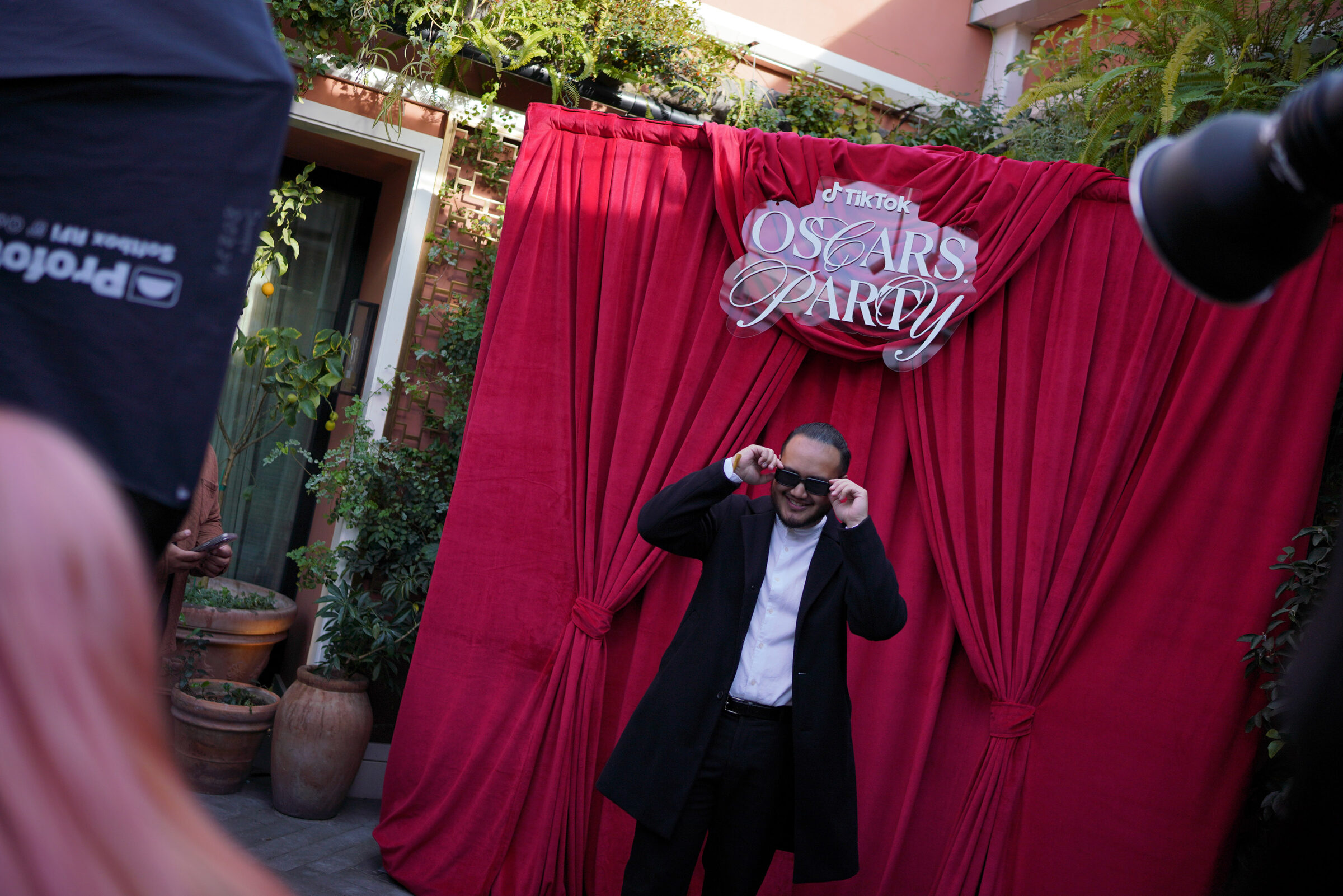 A creator posing in front of the red velvet TikTok Oscars Party photo moment