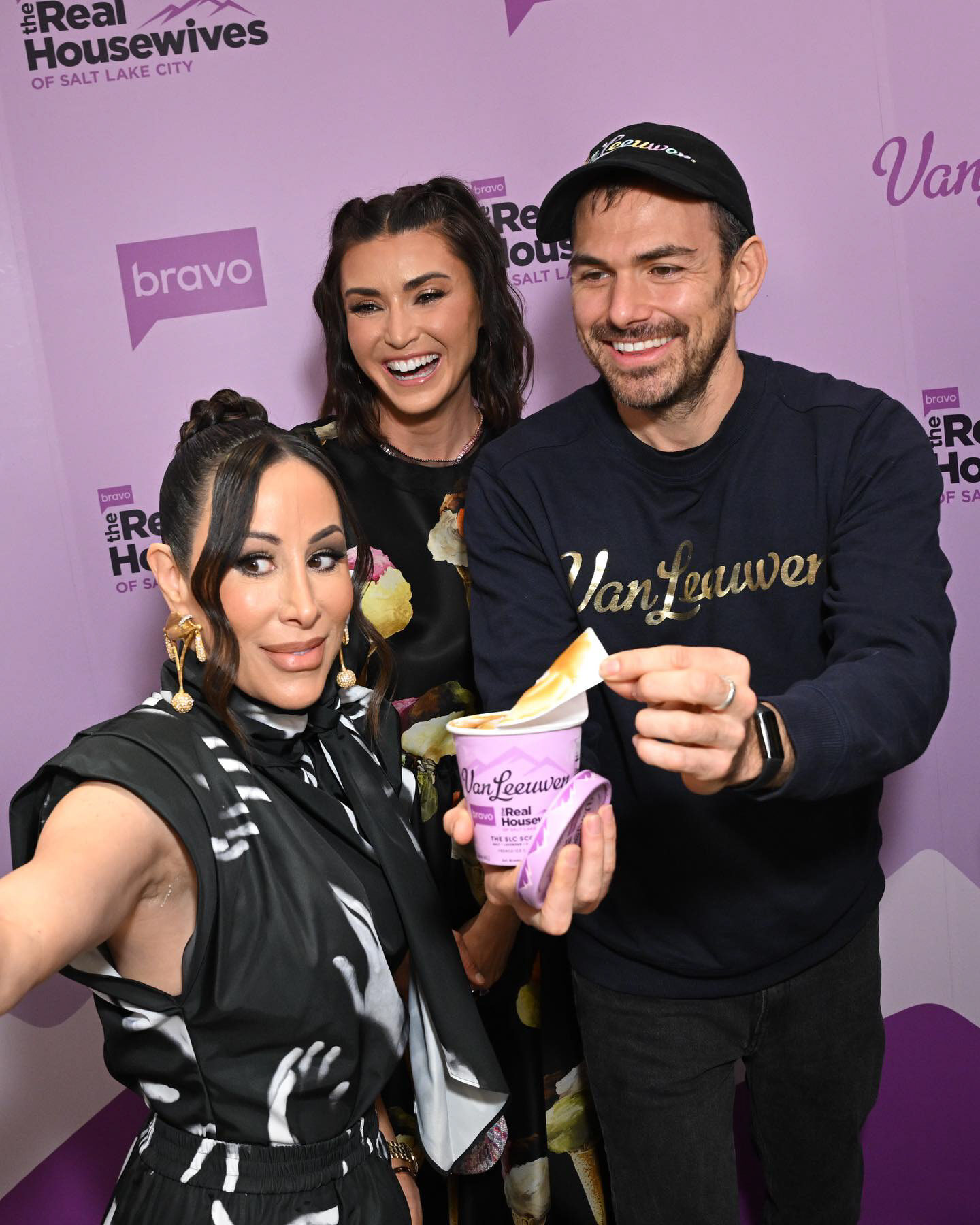 Cast selfie with an SLC Scoop pint in front of the branded wall